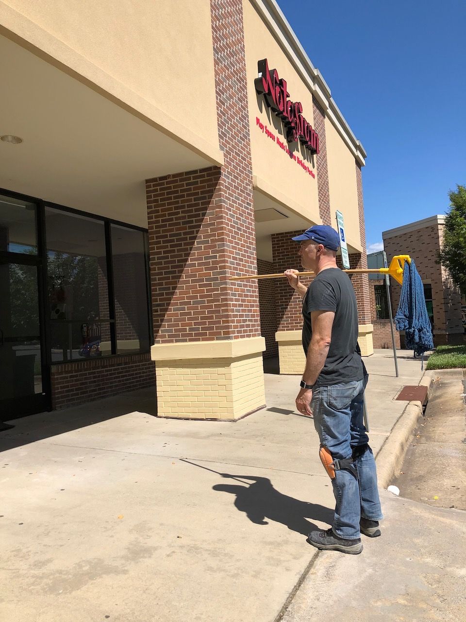 Man carrying cleaning gear in front of store